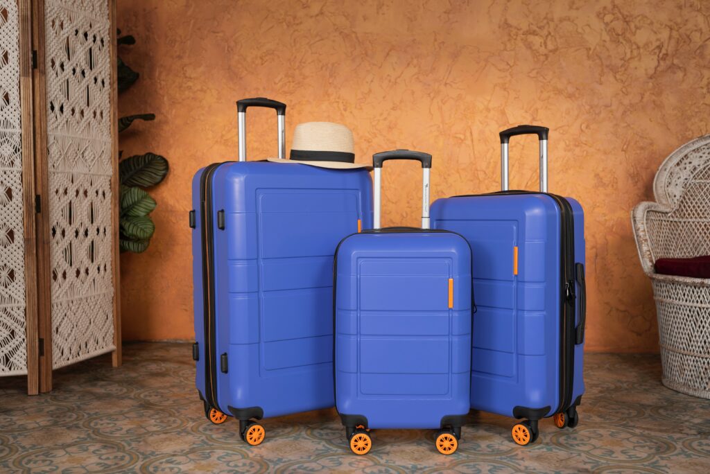 3 Blue Suitcases next to each other in front of an orange wall 