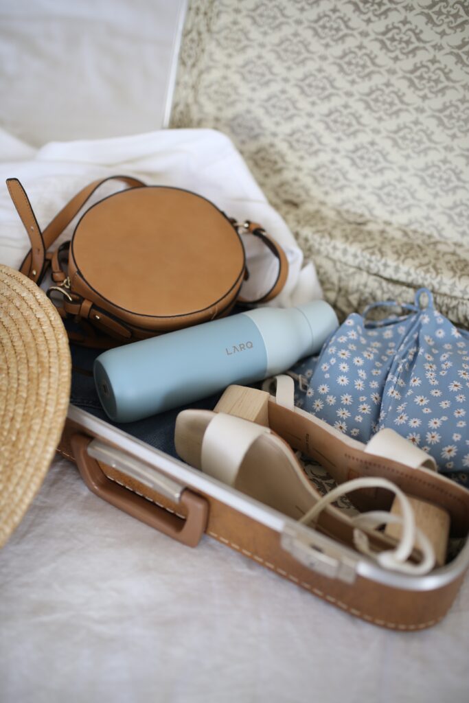 Brown Suitcase filled with bottle, shoes, and bags