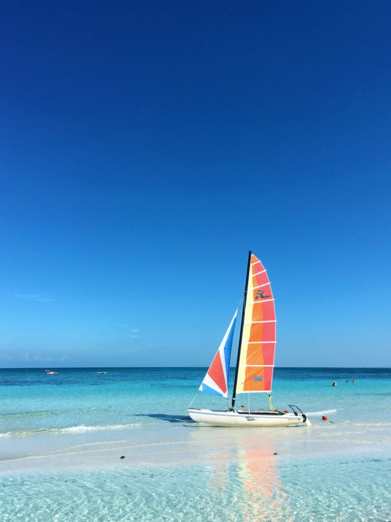 small sail boat on beach with blue waters