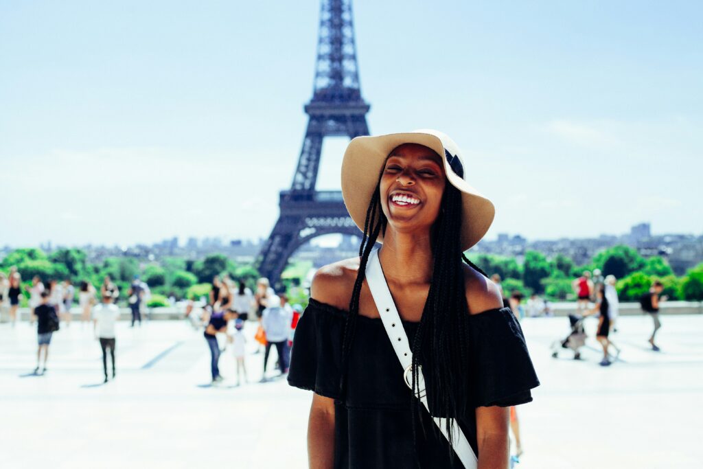 Single Woman Smiling in front of Eiffel Tower, Paris To display The Benefits of Solo Travel 