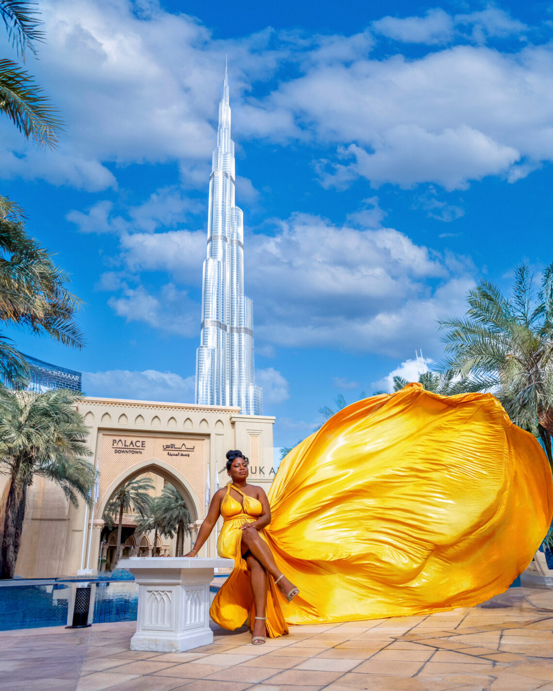 Woman in yellow flying dress in Downtown Palace Dubai with Burj Khalifa in background